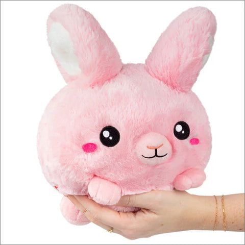 Image shows a pink stuffed bunny with tall ears being held in someone's palm