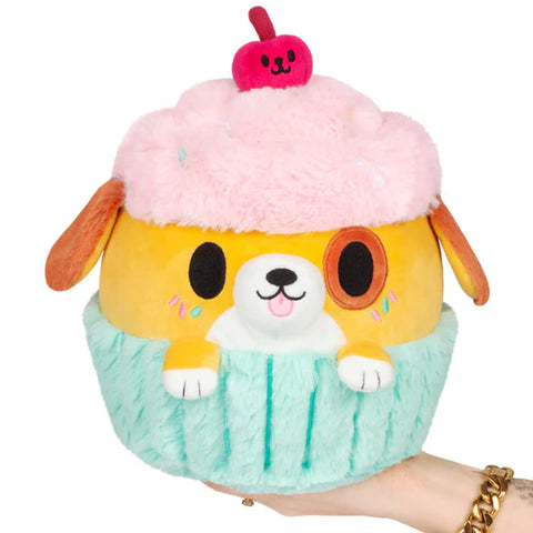 Image shows a stuffed pupcake - half puppy and half cupcake. The puppy sits between the cupcake tin and the frosting.