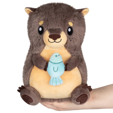 Image shows a seated stuffed river otter holding a blue fish