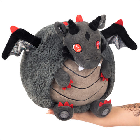 A grey dragon with red accents and black horn and wings, held in someone's hand.