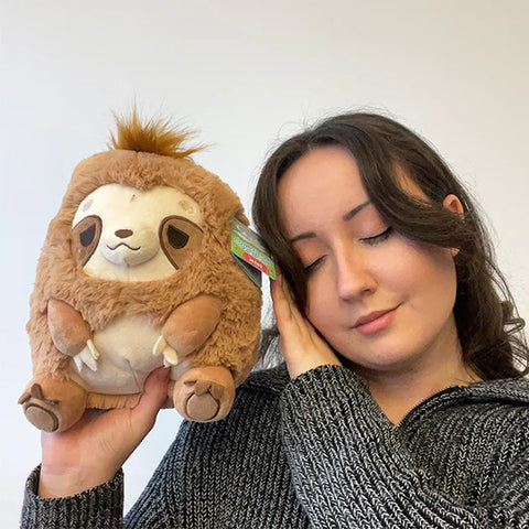 Image shows a woman holding the stuffed sloth up to her face. It is approximately the size of her head.