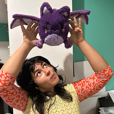 Image shows a woman holding the bat above her head with its wings out. It is slightly larger than her head.