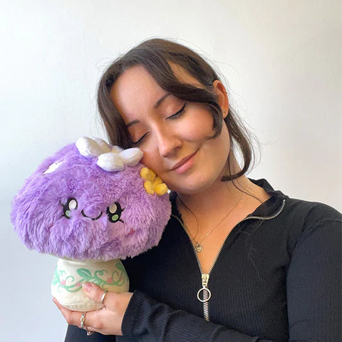 Image shows a woman holding the pastel purple mushroom up to her face. It is slightly larger than her head.