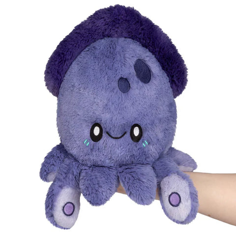 Purple plush squid toy held by a hand on a white background