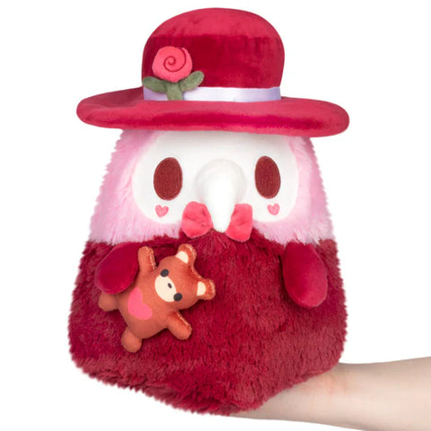 Image shows the valentine's themed Plague Doctor. He is red and pink and is holding a teddy bear.