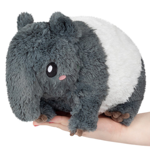A plush toy resembling a tapir, with a gray body and white belly, being held in a person's hand.