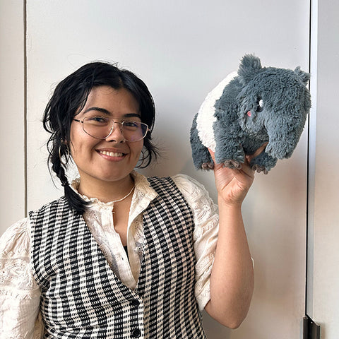 A woman holds the plush Tapir. It is slightly larger than her head.