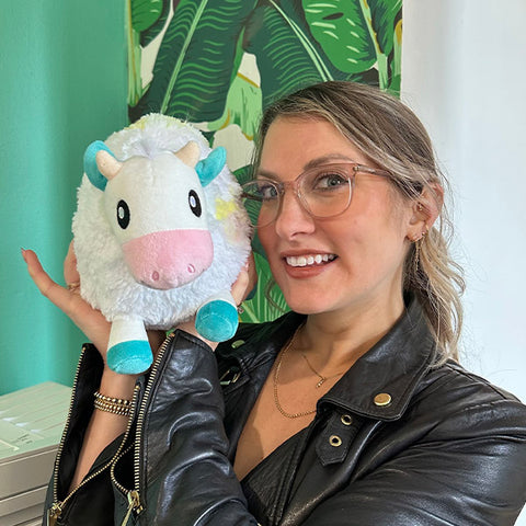 Image shows a woman holding the tie dye cow up to her face. It is approximately the size of her head.