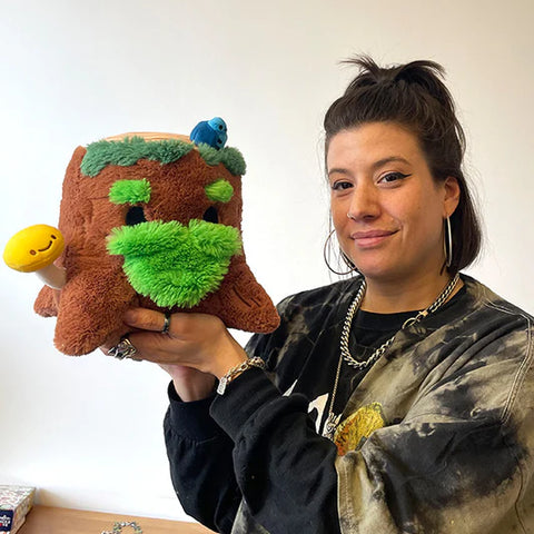 Image shows a woman holding up the stuffed tree stump. It is approximately the size of her head.