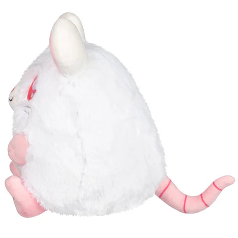 A side view of the stuffed white rat. You can see its skinny pink tail