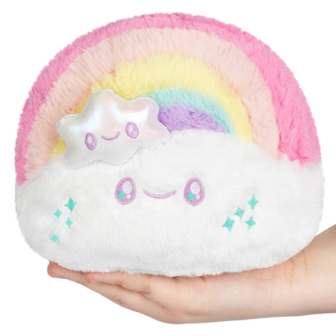 Plush toy cloud with rainbow and smiley face held in a hand on a white background