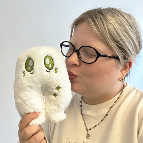 A woman holds the plush nightcrawler near her face. It is slightly smaller than her head.