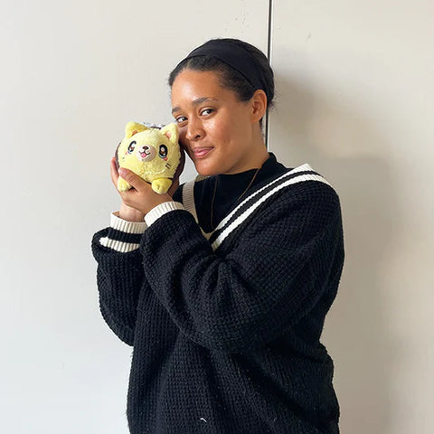 Image shows a woman holding the stuffed cat bee up to her face. It is about half the size of her head.