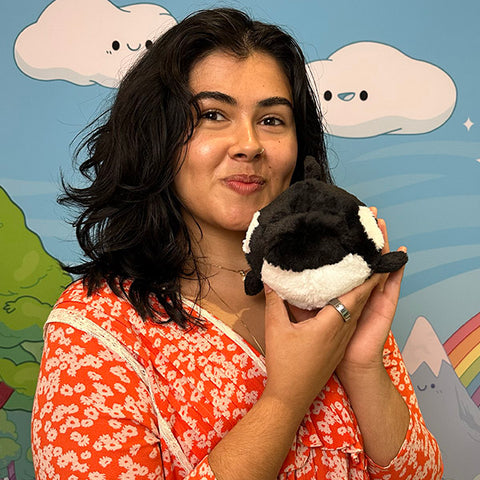 Image shows a woman holding the stuffed orca whale. It is slightly smaller than her head.