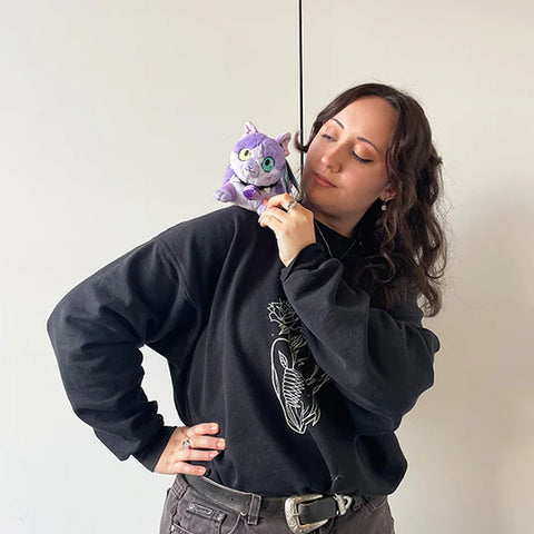 Image shows a woman holding the stuffed phlox cat on her shoulder. It is a bit smaller than her head.