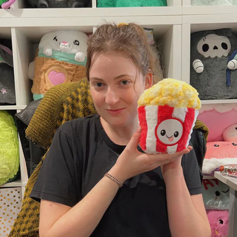 Image shows a woman holding the stuffed popcorn up to her face. It is slightly smaller than her head.