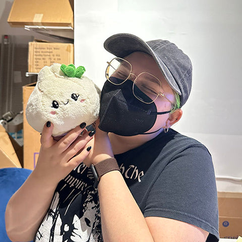 Image shows a masked woman holding the stuffed soup dumpling. It is slightly smaller than her head.