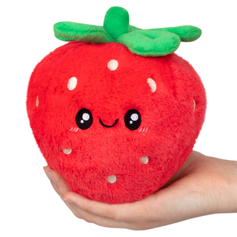 A plush toy shaped like a strawberry with a face, held in a person's hand.