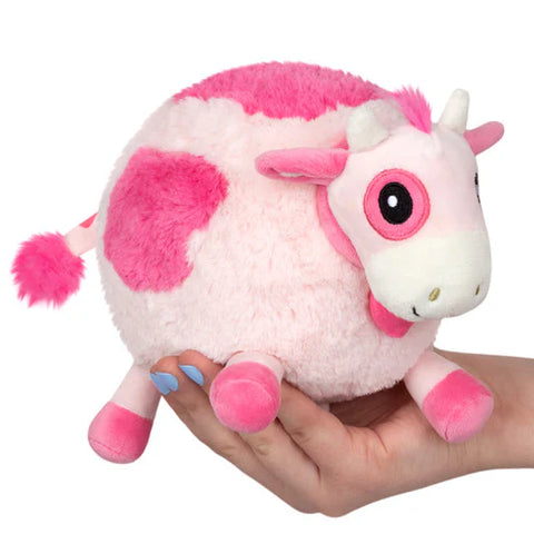Image shows a stuffed pink cow held in someone's hand