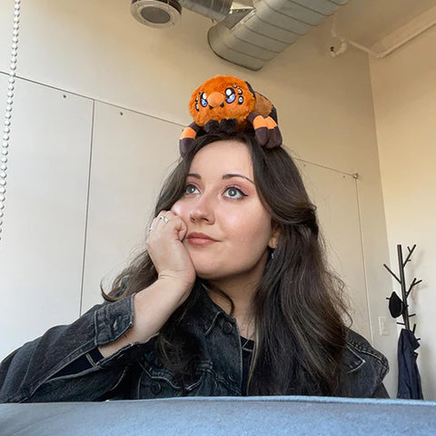Image shows a woman with the stuffed tarantula on top of her head. It is slightly smaller than her head.
