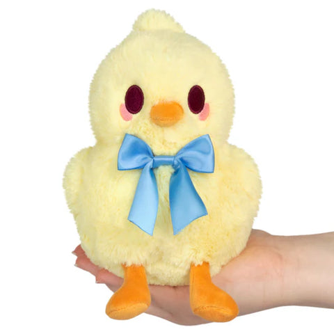 Image shows a stuffed chick with a blue bow at its collar. It is being held in someone's palm.