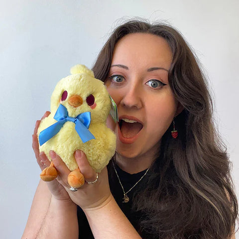 Image shows a woman holding the chick up to her face. It is slightly smaller than her head.