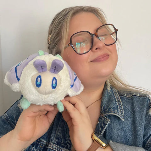 Image shows a woman holding the stuffed luna moth. It is about the size of half of her head.
