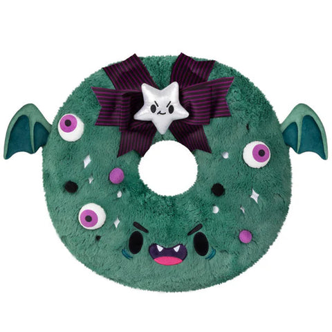 Image shows a stuffed spooky wreath. It has an angry face, eyeballs, and bat wings.