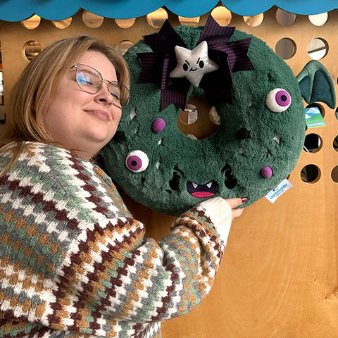Image shows a woman holding the stuffed spooky wreath. It is quite a bit larger than her head.