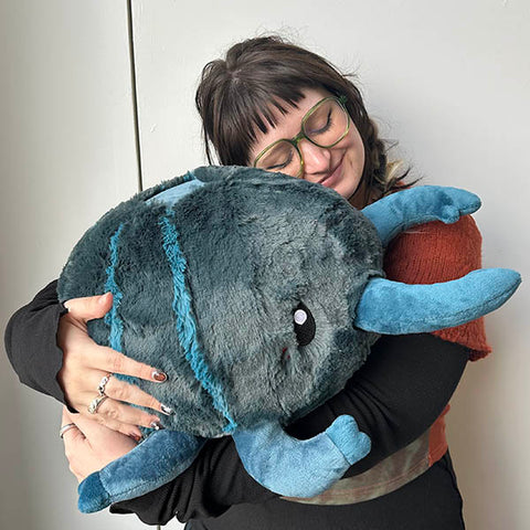 Image shows a woman hugging the stuffed stag beetle. It is approximately the size of her torso.