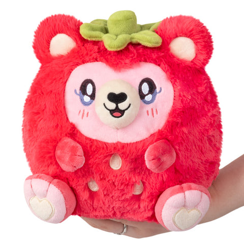A plush toy resembling a strawberry bear with a red body, white and pink accents, and a green top.