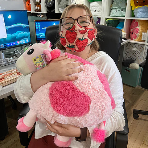 Image shows a woman holding the pink stuffed cow. It is approximately the size of her torso.