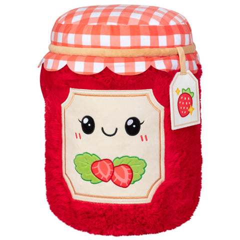 A plush toy shaped like a jar of strawberry jam with a gingham lid, smiling face label, and strawberries on the label.