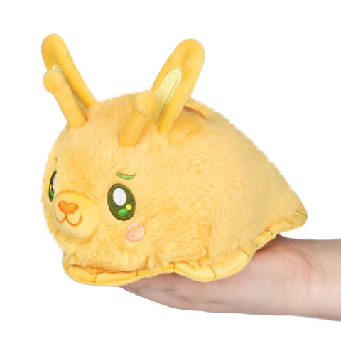 Image shows a stuffed yellow slug with a bunny face and ears. It rests in someone's palm.