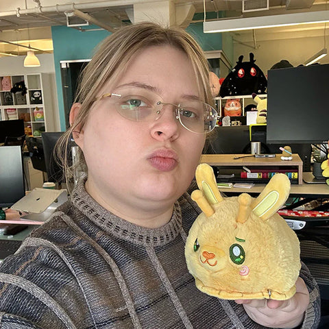 Image shows a woman holding the stuffed bunny slug. It is about half the size of her face,