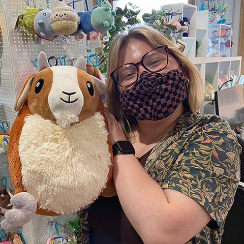 Image shows a woman holding the stuffed goat. It is larger than her head.
