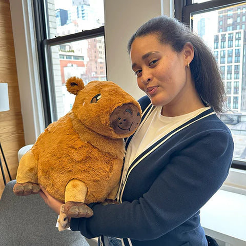 Image shows a woman holding the stuffed Capybara. It is approximately the size of her chest.