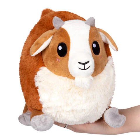 Image shows a stuffed baby goat resting on someone's hand. The goat is very round.