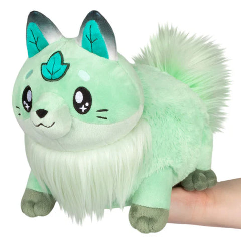 Image shows a minty green stuffed fox. It has a fluffy chest and tail, a leaf on its forehead, and leaves in its ears.