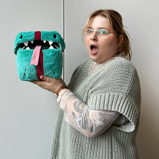 A blonde woman holds the stuffed gift up. It is appoximately the same size as her head.