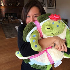 Image shows a woman hugging the stuffed sea turtle. It is approximately the size of her torso.