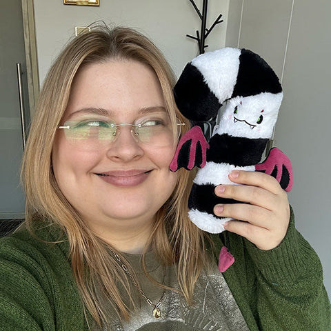 A woman holds the same evil candy cane to her face. It is approximately the same length as her face.