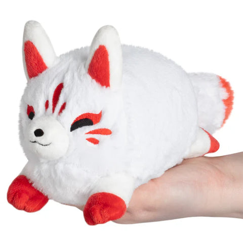 Image shows a white Stuffed Kitsune with dark orange accents. It is sitting in the palm of someone's hand.