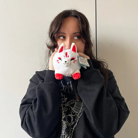 Image shows a woman holding the stuffed Kitsune. It is about half the size of her face.