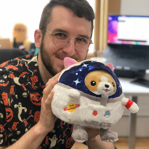 Image shows a man holding the astronaut Corgi. It is slightly larger than his head.