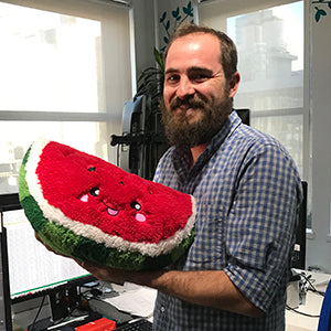 Image shows a man holding the stuffed slice of watermelon. It is about the size of his chest.