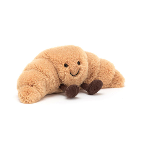 Plush toy shaped like a croissant with a happy face and feet on a white background