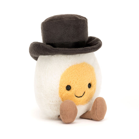A stuffed hardboiled egg with a black top hat. The yolk has a happy face and the egg has feet.