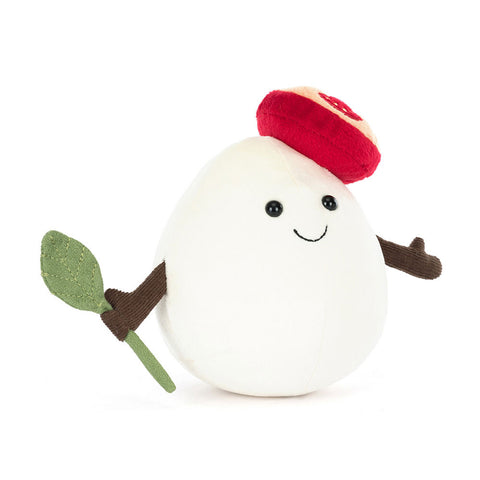Image shows a stuffed ball of mozzarella cheese. It is wearing a tomato hat and is holding a basil leaf.