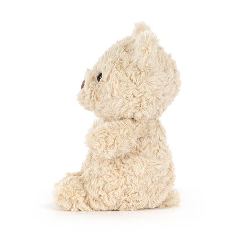 Side view of a fluffy beige teddy bear on a white background
